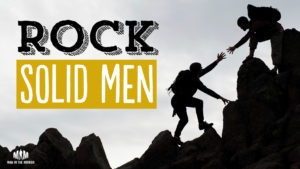 Rock Solid Men - one man helping another up a steep rocky trail
